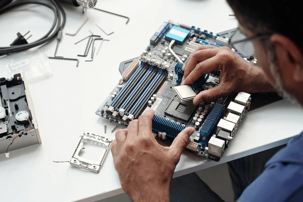 Hands working on a PC motherboard during assembly